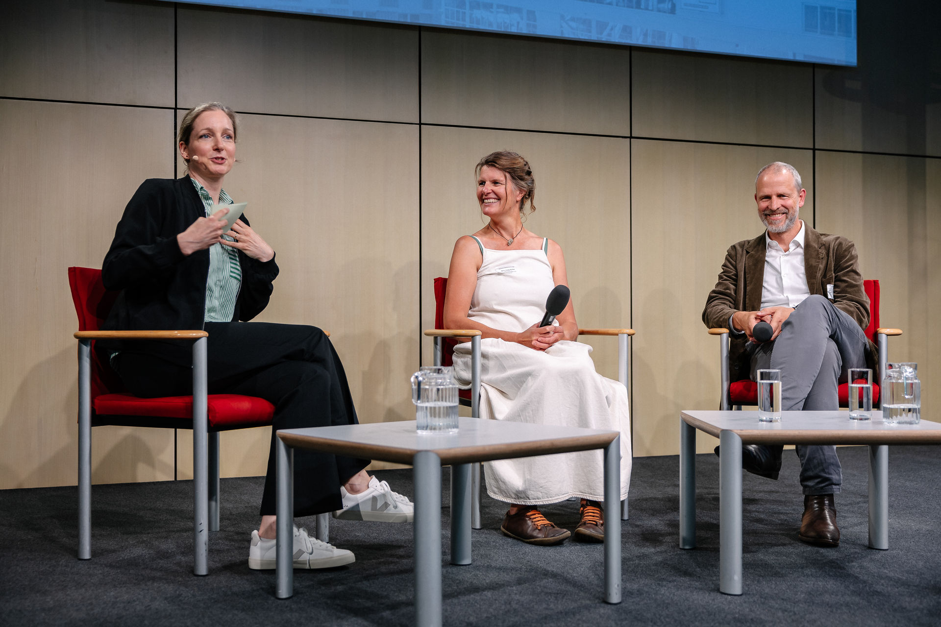 Carolin Kleist im Gespräch mit zwei Gästen auf einem Podium